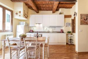 フィレンツェにあるUna Finestra su Firenzeの白いキャビネット、テーブルと椅子付きのキッチンが備わります。