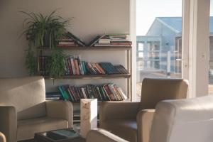 um quarto com duas cadeiras e uma estante de livros com livros em Hótel Eldhestar em Hveragerði