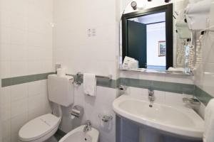 a bathroom with a toilet and a sink and a mirror at Hotel Tirreno in Genoa