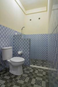 a bathroom with a toilet and a blue tiled wall at Tanaya Homestay in Amed