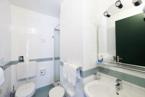 a bathroom with a toilet and a sink and a mirror at Hotel Tirreno in Genoa