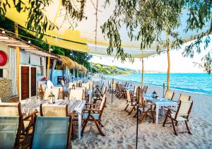 a beach area with chairs, tables and umbrellas at Thracian Cliffs Golf & Beach Resort in Kavarna