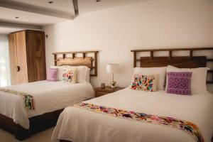 a bedroom with two beds with pillows at El Paraiso Hotel Tulum in Tulum
