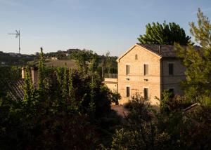 una vecchia casa in pietra con alberi di fronte di Grande villa storica per vacanze con giardino privato e piscina a Ostra