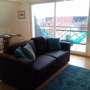 a black couch in a living room with a balcony at Balcon avec vue panoramique de la mer, le village et la campagne - parking privé in Wimereux