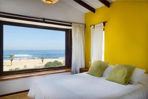 1 dormitorio con 1 cama y ventana grande con playa en Cabañas, Habitaciones y Restaurant Montemar en El Tabo