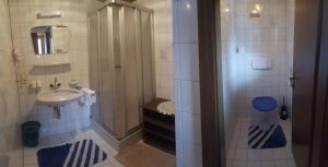 a bathroom with a sink and a shower with blue mats at Gästehaus Eberl - Rita in Finkenberg