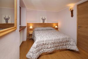 サウゼ・ドゥルクスにあるAppartamenti Genevrisのベッドルーム1室(ベッド1台、ランプ2つ、鏡付)