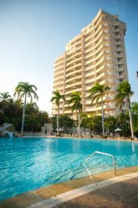 a large hotel with palm trees and a swimming pool at Irotama Apartasuites in Santa Marta