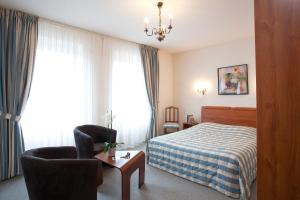 une chambre d'hôtel avec un lit et une chaise dans l'établissement Logis Hotel-Restaurant De La Poste, à Urmatt