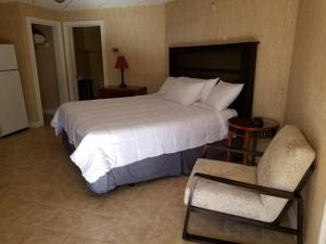 ein Schlafzimmer mit einem großen weißen Bett und einem Stuhl in der Unterkunft Cedar Park Inn in North Stonington