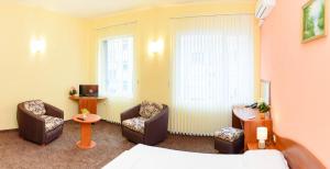 Family Hotel Varna في مدينة فارنا: غرفة بالفندق بها كراسي وسرير وتلفزيون