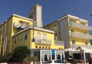 un edificio amarillo con un coche aparcado delante de él en Hotel Verona en Caorle
