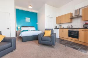 a kitchen and a bedroom with a bed and a chair at Fiveway Apartments in Paignton