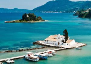 an island with a church and boats in the water at Hebes Studios in Kavos