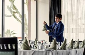 a man in a suit standing in front of a table at All Senses Nautica Blue Exclusive Resort & Spa - All Inclusive in Fánai
