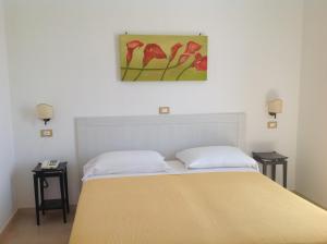 a bedroom with a bed with a painting on the wall at Hotel Corallo in Torre Santa Sabina