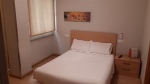 een kleine slaapkamer met een wit bed en een raam bij PR Blanco in Santiago de Compostela