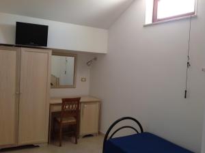 a room with a bed and a desk and a television at Hotel Corallo in Torre Santa Sabina