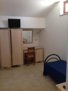 a room with a bed and a desk with a television at Hotel Corallo in Torre Santa Sabina