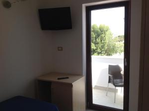 a room with a door leading to a balcony with a chair at Hotel Corallo in Torre Santa Sabina