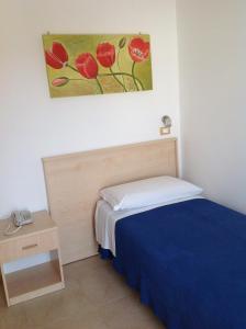 a bedroom with a bed and a painting on the wall at Hotel Corallo in Torre Santa Sabina