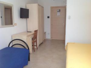 Habitación pequeña con escritorio, cama y puerta en Hotel Corallo, en Torre Santa Sabina