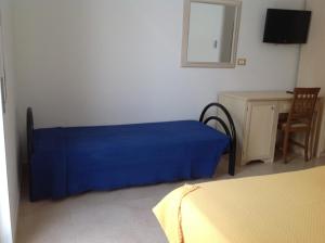 a bed with a blue blanket in a room at Hotel Corallo in Torre Santa Sabina