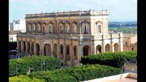a large building with trees in front of it at Maride Holiday in Noto