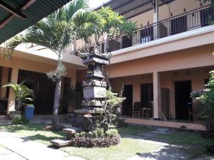 a column in front of a building with palm trees at Puji Homestay in Mataram
