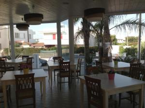 ein Restaurant mit weißen Tischen, Stühlen und Palmen in der Unterkunft Hotel Corallo in Torre Santa Sabina