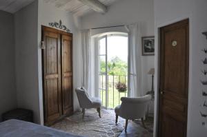 een slaapkamer met een bed en twee stoelen en een raam bij Le Mas En Provence in Entrechaux