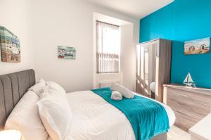 a bedroom with a bed with a blue accent wall at Fiveway Apartments in Paignton