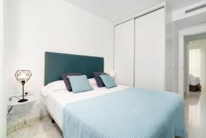 バレンシアにあるFlatsforyou Ruzafaの白いベッドルーム(青い枕の大型ベッド付)