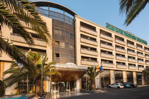 a large building with palm trees in front of it at Elba Vecindario Aeropuerto Business & Convention Hotel in Vecindario