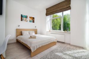 a white bedroom with a bed and a window at Family apartments 2 in Vilnius