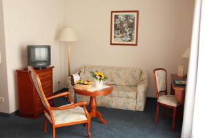 sala de estar con sofá y mesa con TV en Hotel Ascania, en Aschersleben