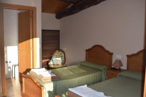 a bedroom with two beds and a chair at Pensión Albergue Los Caminantes in Ribadiso