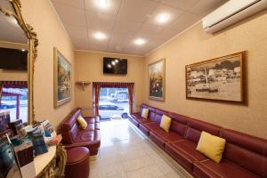 a waiting room with a leather couch and a tv at Hotel Tirreno in Genoa