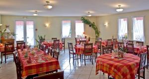 a restaurant with tables and chairs with red tablecloths at Hotel De La Poste in Saint-Martin-sous-Vigouroux