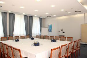 une grande salle de réunion avec une table et des chaises blanches dans l'établissement Hotel Ascania, à Aschersleben