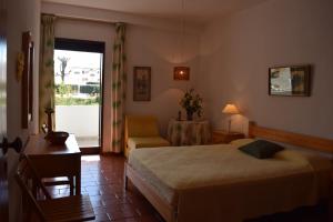 Roja- PéにあるApartamento T2 com Piscina e Wifi a 350 metros da Praiaのベッドルーム1室(ベッド1台、椅子、テーブル付)