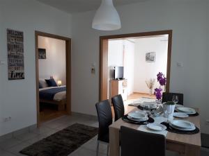 a dining room with a table and chairs and a bedroom at Hanna Apartman in Bük