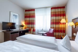 フランクフルト・アム・マインにあるTrip Inn Frankfurt Nordwestzentrumのベッド、デスク、テレビが備わるホテルルームです。