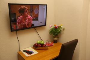 a television hanging on a wall above a table with fruit at Hotel AI Königshof in Berlin