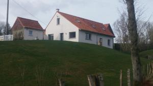 a white house on top of a green hill at les gîtes de la cuesta in Henneveux