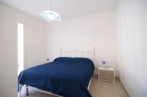 ein weißes Schlafzimmer mit einem Bett mit einer blauen Decke in der Unterkunft Aria di Mare in Casal Velino