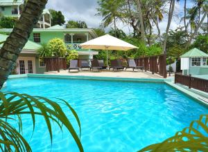a large blue swimming pool with chairs and an umbrella at Marigot Beach Club & Dive Resort in Marigot Bay