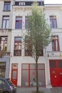 a tree in front of a building with red doors at Because the Night city lodge in Antwerp