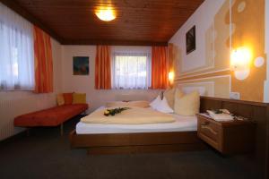 - une chambre avec un grand lit et un canapé rouge dans l'établissement Haus Öttl, à Ischgl